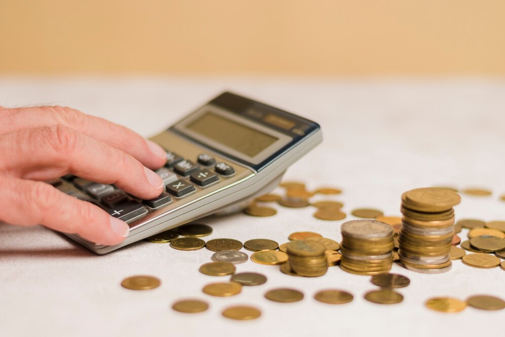 calculadora rodeado de moedas para simbolizar a contagem de dinheiro e cálculo de redução de custos